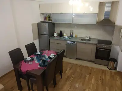 a kitchen with a table and chairs and a kitchen with a table and a table at Apartments Svilen Konac in Budva