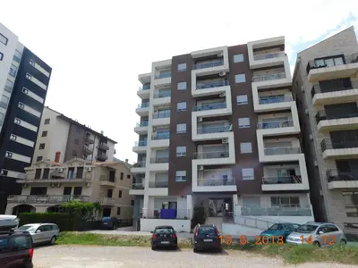 a tall apartment building with cars parked in a parking lot at Apartments Svilen Konac in Budva