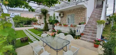 a patio with a glass table and white chairs at Apartments Cota Guesthouse in Ulcinj