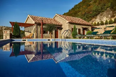 a house with a swimming pool next to a mountain at Eco Resort Cermeniza in Virpazar