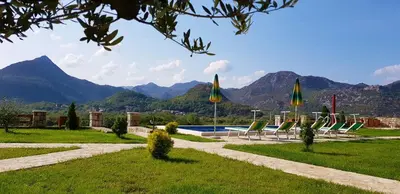 a group of lawn chairs and umbrellas near a pool at Eco Resort Cermeniza in Virpazar