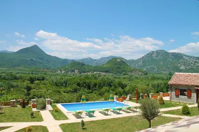 a villa with a swimming pool and mountains in the background at Eco Resort Cermeniza in Virpazar