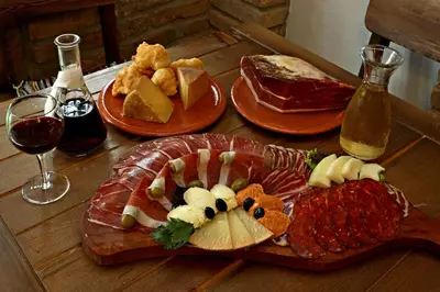 a wooden table with plates of food and glasses of wine at Eco Resort Cermeniza in Virpazar