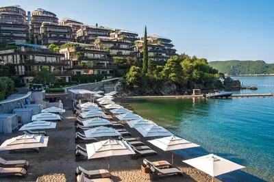 a row of beach chairs and umbrellas on a beach at Duklej Apartment LUX in Budva