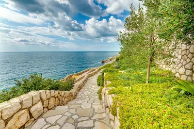 a stone path next to a stone wall next to the ocean at Sveti Luka Apartments in Dobra Voda