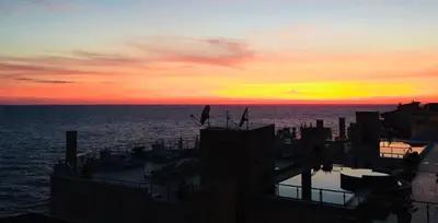 a sunset over the ocean with buildings and the water at Sveti Luka Apartments in Dobra Voda