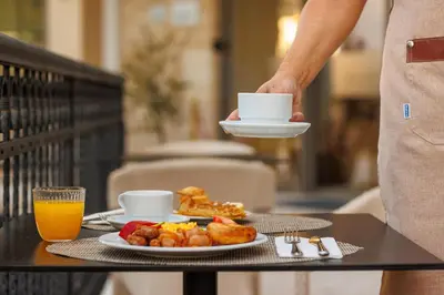 a man holding a cup of coffee and a plate of food at Hotel Kadmo by Aycon in Budva