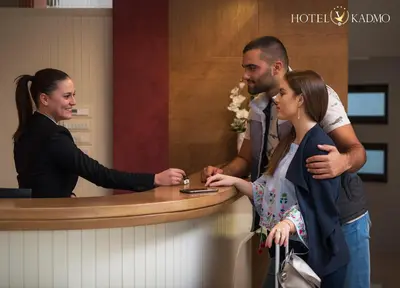 a man and a woman standing at a counter at Hotel Kadmo by Aycon in Budva