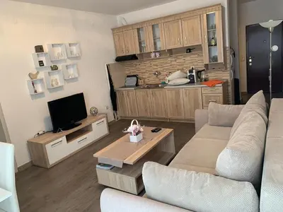 a living room with a couch and a tv and a kitchen at Apartman Glava Zete in Sutomore