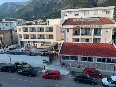 a parking lot with cars parked in front of a building at Apartman Glava Zete in Sutomore