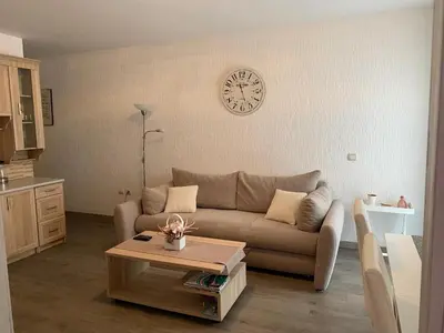 a living room with a couch and a clock on the wall at Apartman Glava Zete in Sutomore