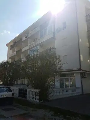 a tall white building with the sun shining on it at Apartman Glava Zete in Sutomore