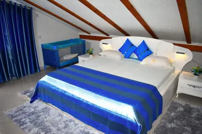 a bedroom with a blue and white bed with blue pillows at Guest House Aldin in Ulcinj