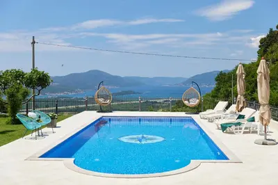 a swimming pool with chairs and a view of the ocean at Carpe Diem Apartments in Kotor