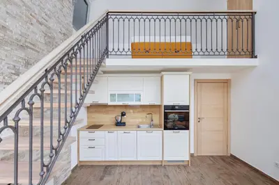 a kitchen with white cabinets and a spiral staircase at Carpe Diem Apartments in Kotor