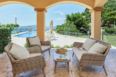 a patio with two chairs and a table and a pool at Carpe Diem Apartments in Kotor