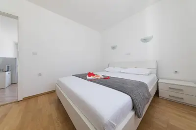 a white bedroom with a white bed with a gray blanket at Apartments Tamaris in Tivat