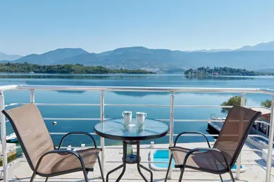 a table and chairs on a balcony with a view of a lake at Apartments Tamaris in Tivat