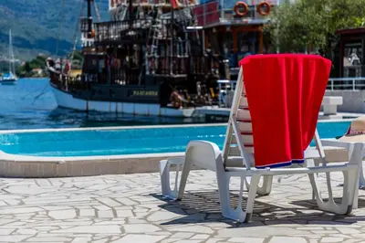 a chair with a red blanket sitting next to a pool at Apartments Tamaris in Tivat