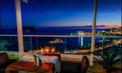 a dining room with a view of the ocean at night at Luxury Apartments Mia in Budva