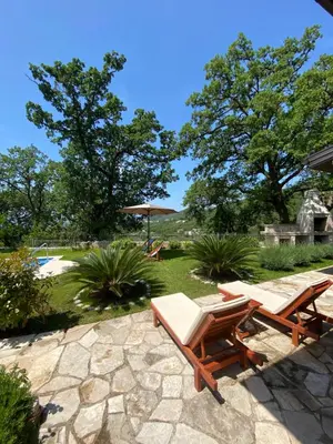 a patio with two lounge chairs and an umbrella at El Mar House in Petrovac na Moru