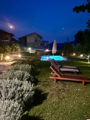 a group of lounge chairs and a pool at night at El Mar House in Petrovac na Moru