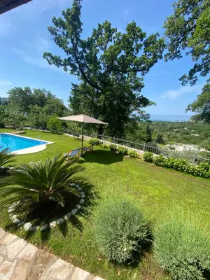 a garden with a swimming pool and an umbrella at El Mar House in Petrovac na Moru
