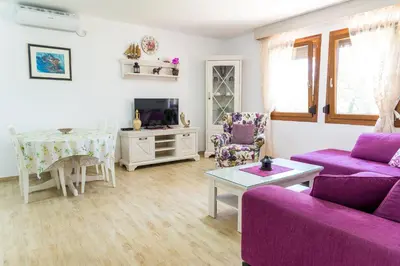 a living room with purple couches and a tv at El Mar House in Petrovac na Moru