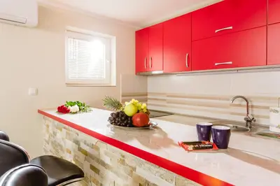 a kitchen with red cabinets and a bowl of fruit on a counter at Sea Holiday Muo with Sea and City View in Kotor