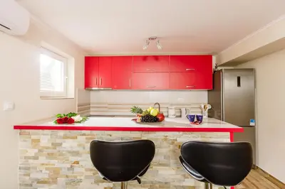 a kitchen with red cabinets and two black chairs at Sea Holiday Muo with Sea and City View in Kotor