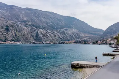 a person standing on the edge of a body of water at Sea Holiday Muo with Sea and City View in Kotor