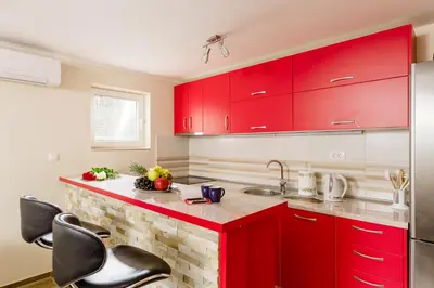 a kitchen with red cabinets and a counter with chairs at Sea Holiday Muo with Sea and City View in Kotor