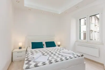 a white bedroom with a large bed and a window at Old Town Summer Apartment in Kotor