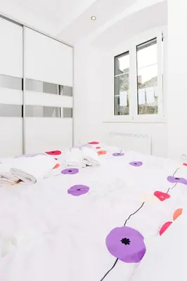 a white room with a bed with purple umbrellas on it at Old Town Summer Apartment in Kotor