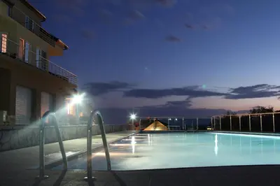 a swimming pool at night with lights on a building at Zubci mountain apartment in Bar