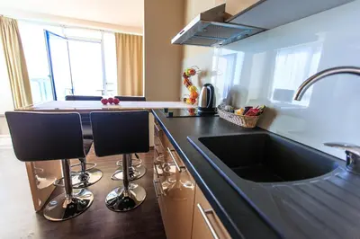 a kitchen with a sink and two bar stools at Atlantic Hotel in Dobra Voda
