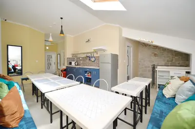 a room with tables and chairs and a kitchen at Hostel Pupa in Kotor