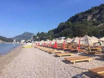a beach with a bunch of umbrellas and benches at Holiday Home Aksentijevic in Sutomore