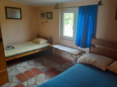 a room with two beds and a window with blue curtains at Star Home in Kotor