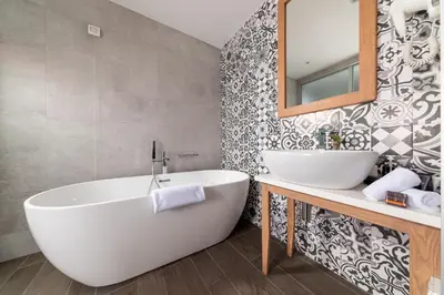 a bathroom with a white tub and a mirror at Hotel Eleven in Petrovac na Moru
