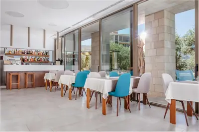 a dining room with white tables and blue chairs at Hotel Eleven in Petrovac na Moru