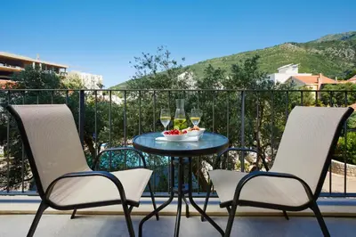 a table with two chairs and wine glasses on a balcony at Hotel Eleven in Petrovac na Moru