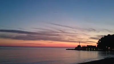 a sunset over a body of water with a pier at Hotel Eleven in Petrovac na Moru