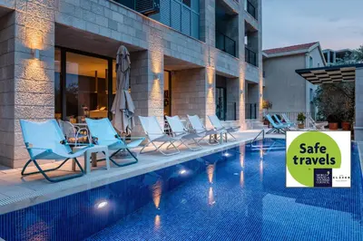 a pool with blue chairs and a sign that says sale travels at Hotel Eleven in Petrovac na Moru