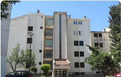 a large white building with a car parked in front of it at Apartment Mika in Budva