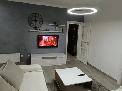 a living room with a couch and a tv on a wall at Apartment Maska in Budva