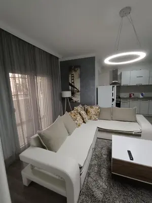 a living room with a white couch and a kitchen at Apartment Maska in Budva