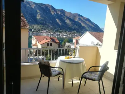 a balcony with a table and chairs and a mountain at Apartments Castello in Kotor