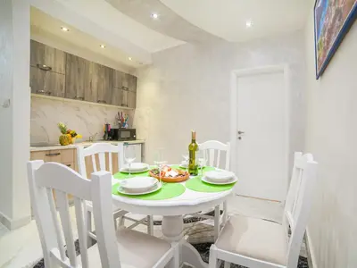 a white dining room with a white table and chairs at Apartments Amigo in Kotor