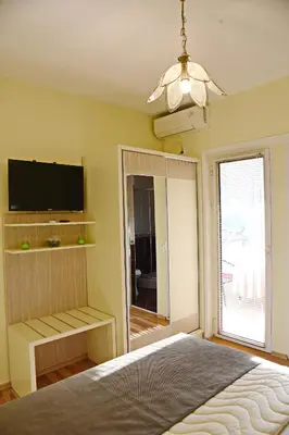 a bedroom with a bed and a tv and a window at Apartments & Rooms Jelka in Kotor